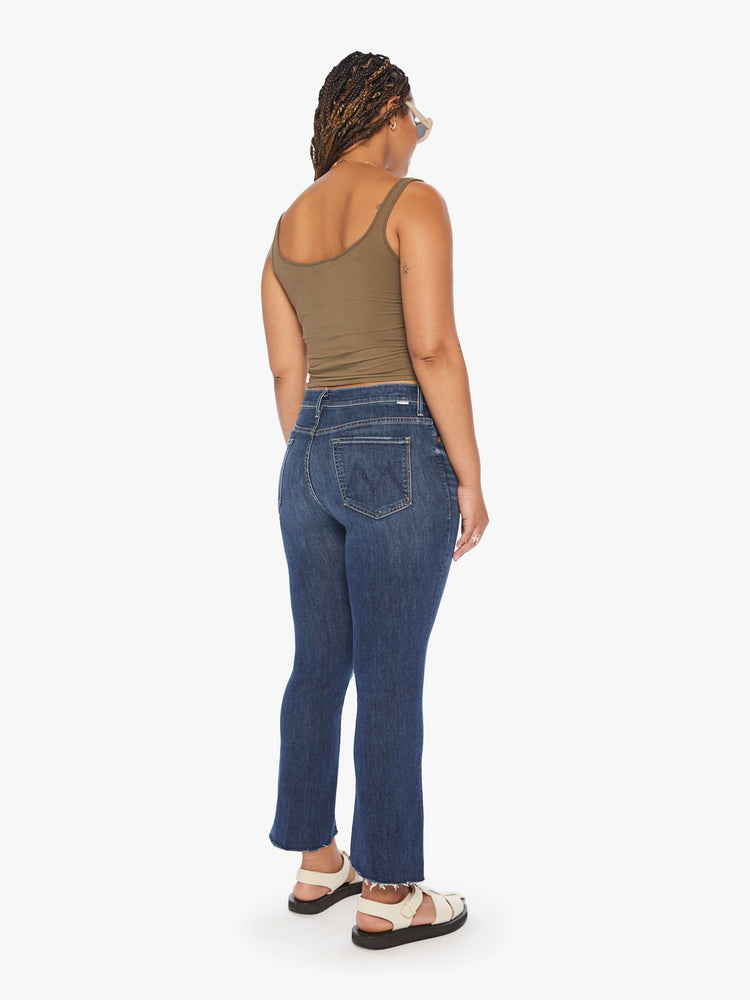 Back view of a womens dark denim wash jean featuring a high rise and a bootcut step fray.
