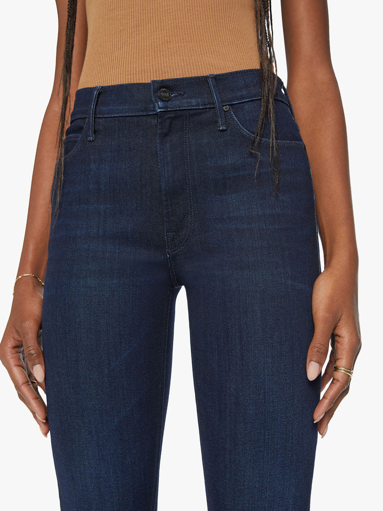 Close up view of a womens mid rise straight leg jean in a dark blue wash and clean hem.