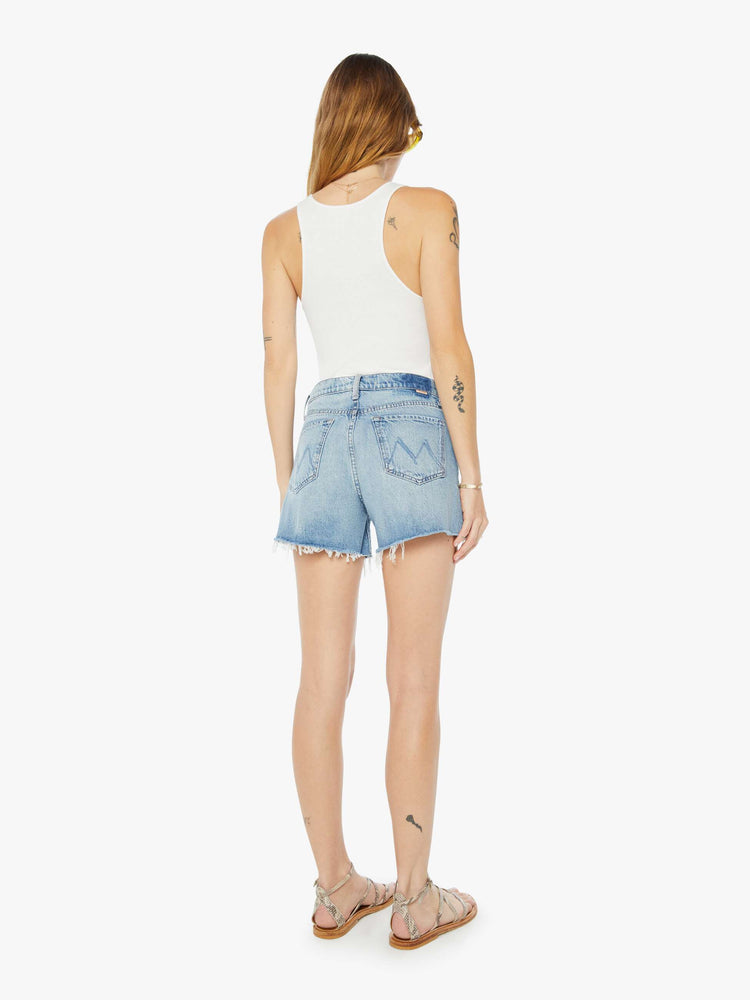 Back view of a womens light blue wash denim short featuring a high rise and frayed hem.