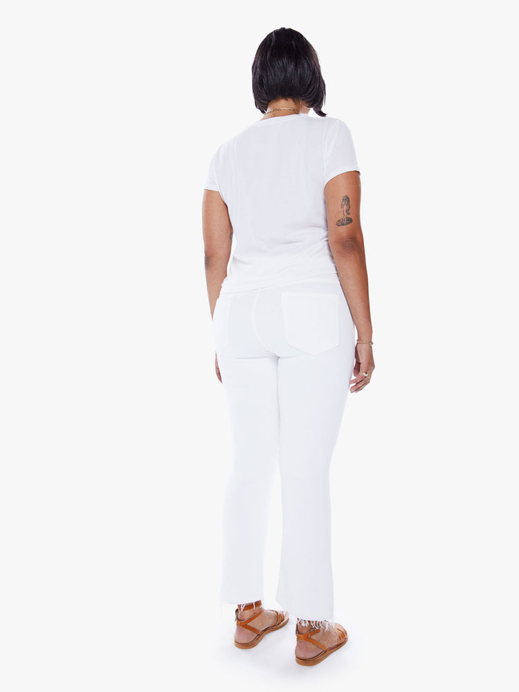Back view of a womens white wash jean featuring a high rise, bootcut, and a crop step frayed hem.