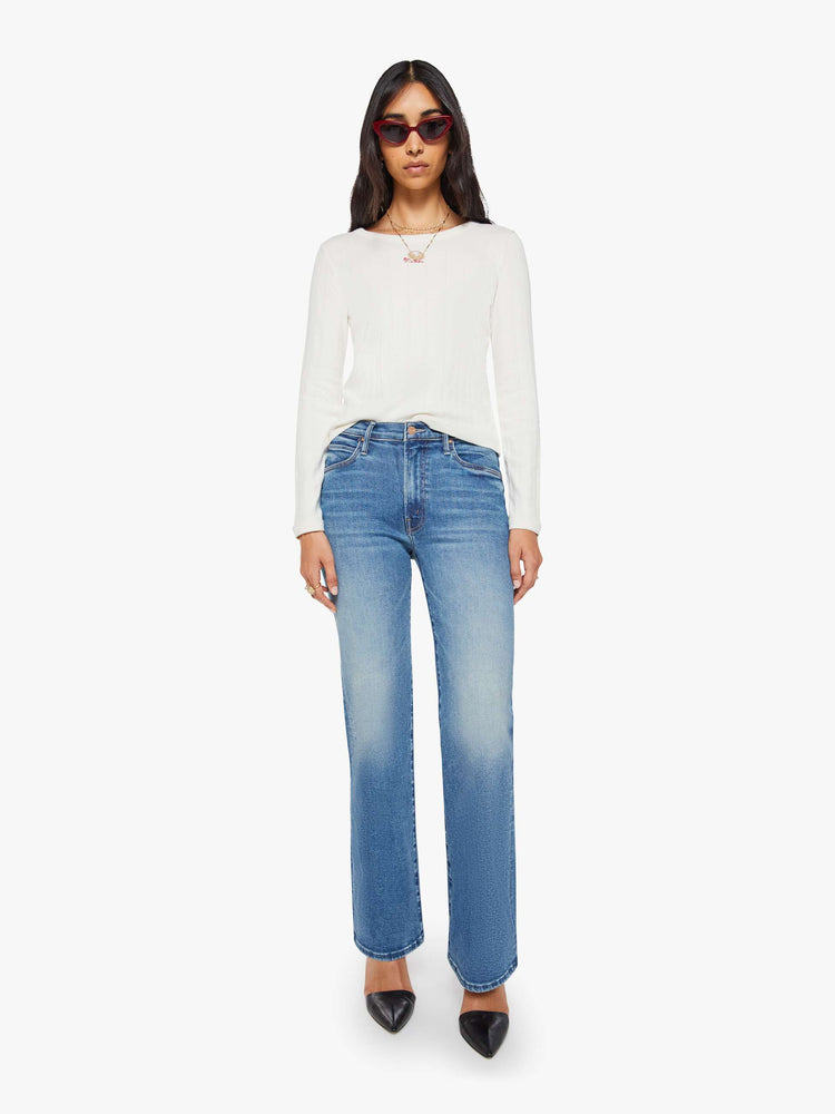 Front view of a woman in a mid blue high-rise straight leg jean with a 32-inch inseam and a clean hem.