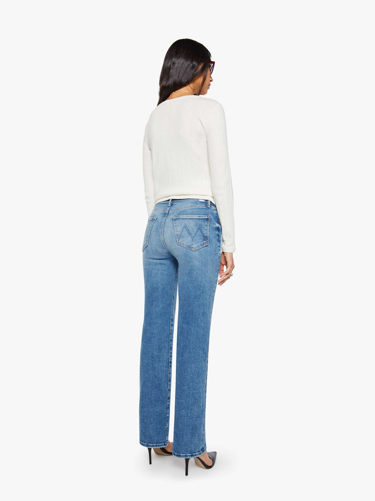 Back view of a woman in a mid blue high-rise straight leg jean with a 32-inch inseam and a clean hem.