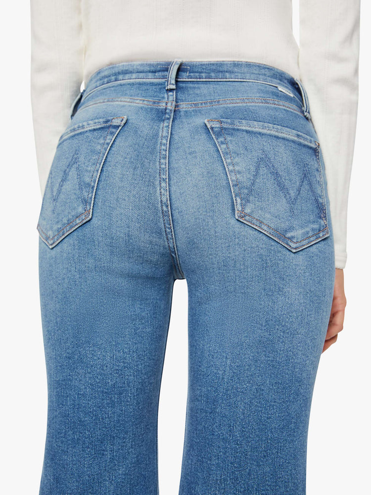 Close up view of a woman in a mid blue high-rise straight leg jean with a 32-inch inseam and a clean hem.