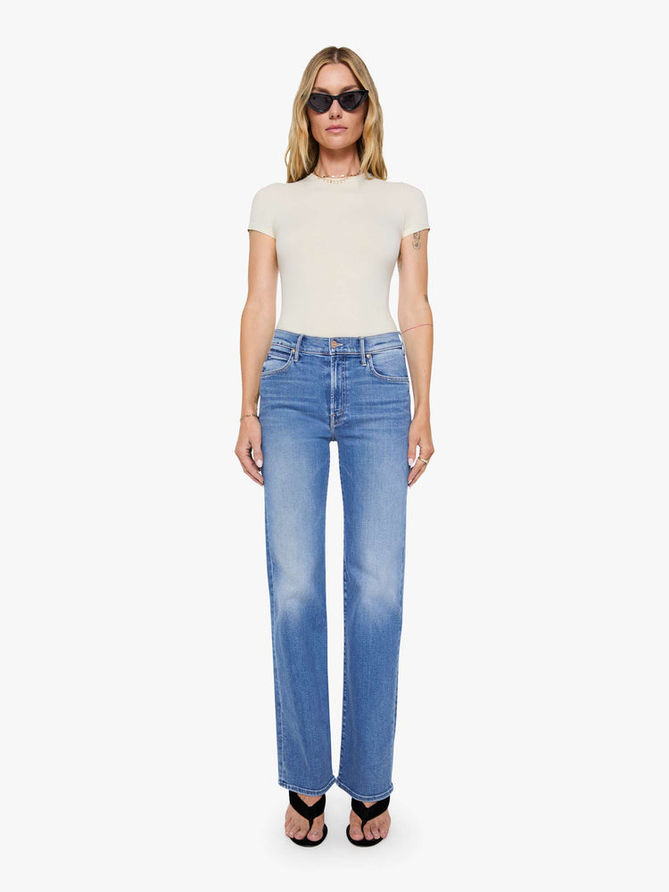 Front view of a woman in mid blue high-rise straight leg jean with a 32-inch inseam and a clean hem.
