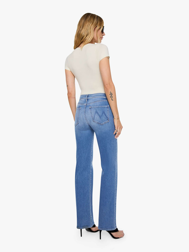 Back view of a woman in mid blue high-rise straight leg jean with a 32-inch inseam and a clean hem.