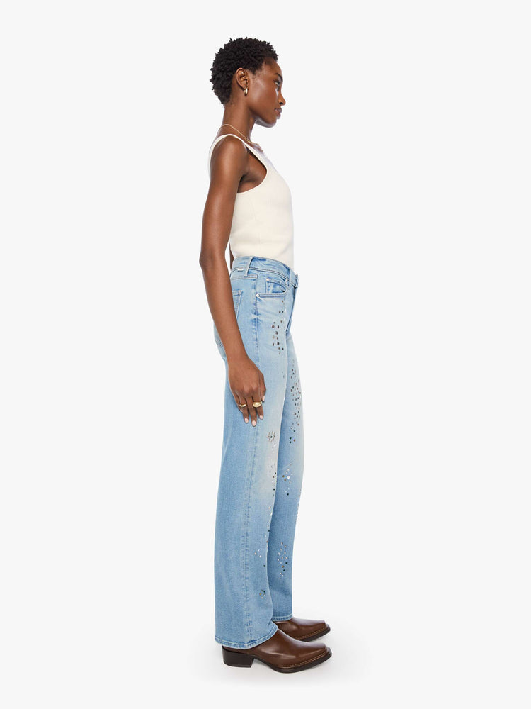 Side view of a woman in a light blue with crystal embellishments high-rise straight-leg jean with a zip fly, 32-inch inseam and a clean hem. 