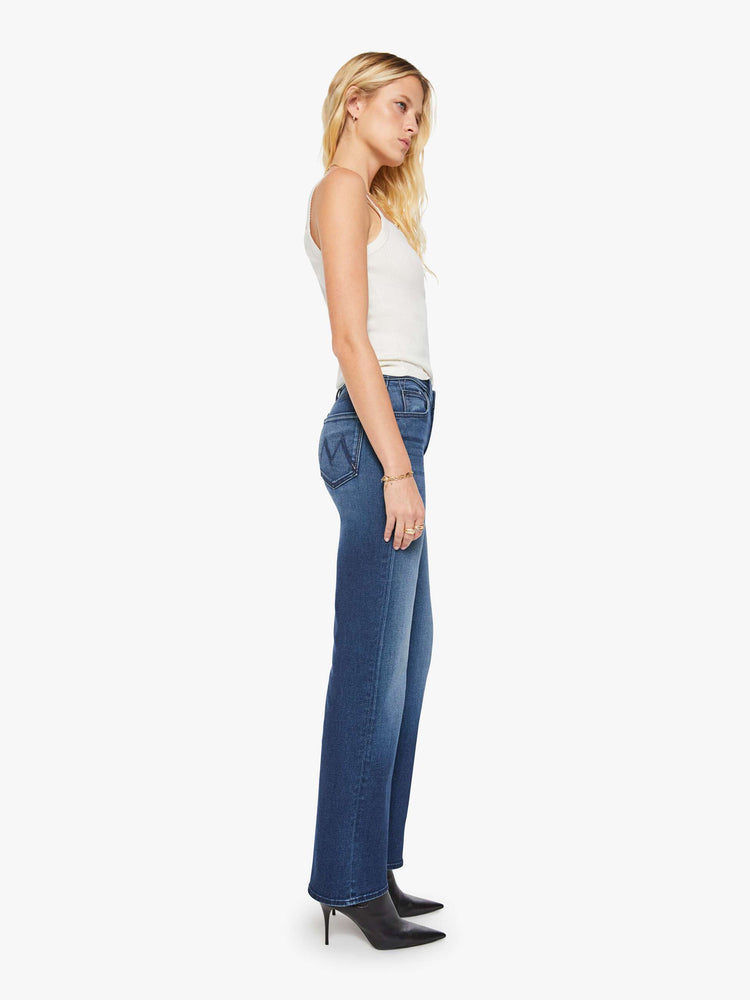 Side view of a woman in a dark blue high-rise straight leg jean with a 32-inch inseam and a clean hem.