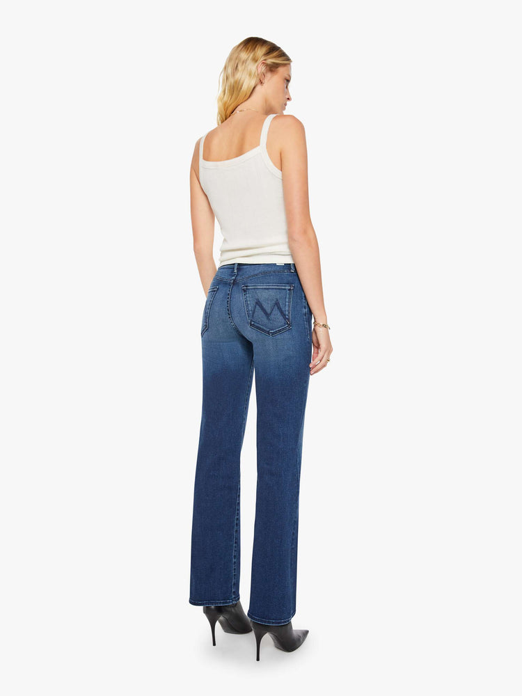 Back view of a woman in a dark blue high-rise straight leg jean with a 32-inch inseam and a clean hem.