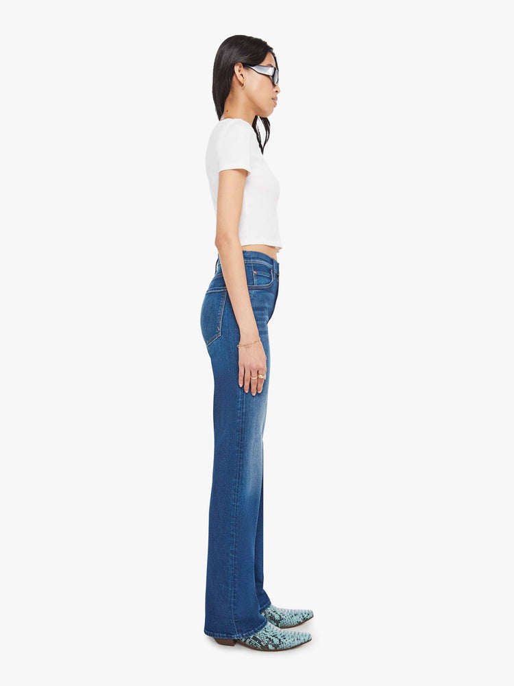 Side view of a med blue high-rise straight-leg jean with a zip fly, 32-inch inseam and a clean hem.