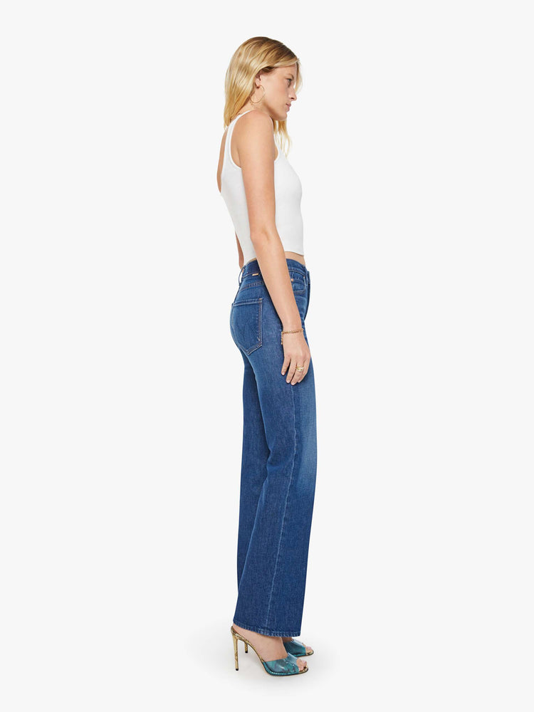 Side view of a woman in a dark blue  high-rise straight leg jean with a zip fly, 32-inch inseam and a clean hem. 