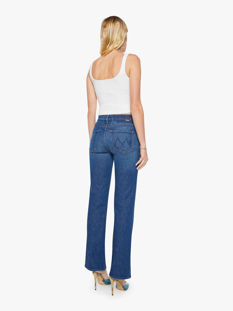 Back view of a woman in a dark blue  high-rise straight leg jean with a zip fly, 32-inch inseam and a clean hem. 