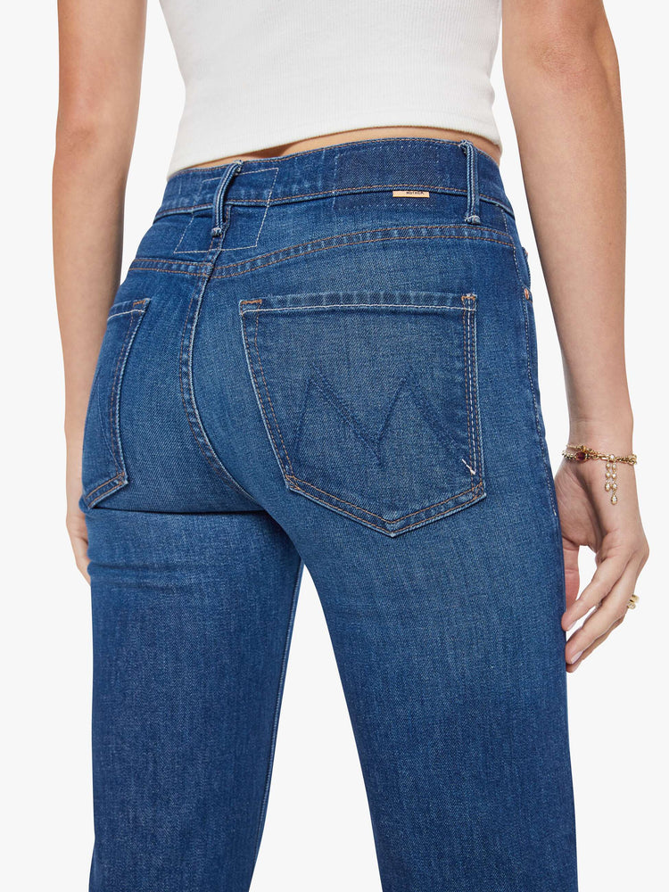 Close up view of a woman in a dark blue  high-rise straight leg jean with a zip fly, 32-inch inseam and a clean hem. 