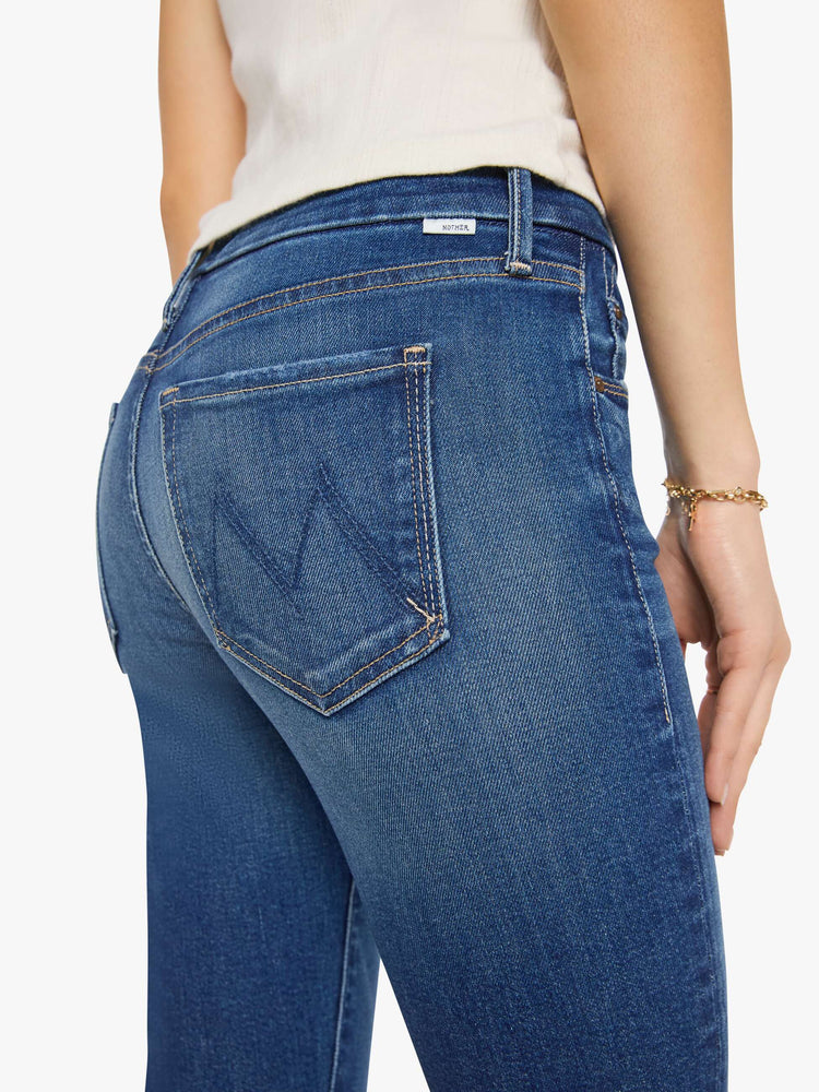 Close up view of a woman in a mid blue skinny jean has a high rise with a zip fly, 29-inch inseam and a clean hem.