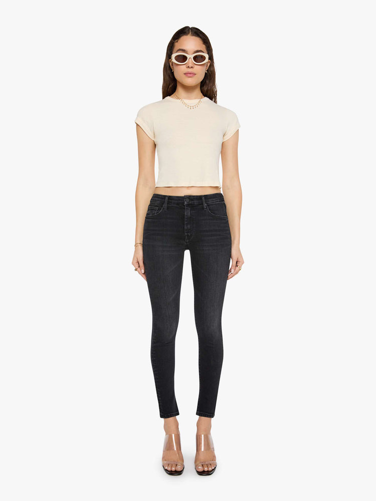 Front view of a woman in a black skinny has a mid rise with a zip fly, 29-inch inseam and a clean hem.