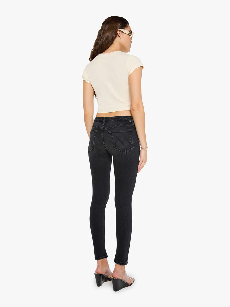 Back view of a woman in a black skinny has a mid rise with a zip fly, 29-inch inseam and a clean hem.