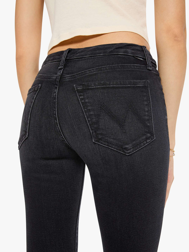 Close up view of a woman in a black skinny has a mid rise with a zip fly, 29-inch inseam and a clean hem.