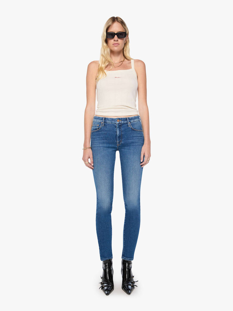 Front view of woman in a med blue skinny jean with a high rise with a zip fly, 30 3/4 inch inseam and a clean hem.