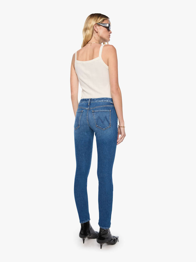 Back view of woman in a med blue skinny jean with a high rise with a zip fly, 30 3/4 inch inseam and a clean hem.