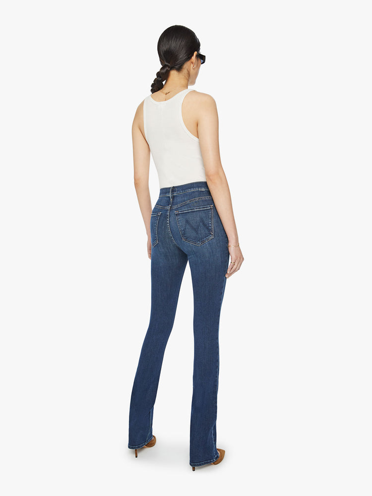 Back view of a woman mid-rise flare with a long 34-inch inseam and a clean hem in a dark blue wash.