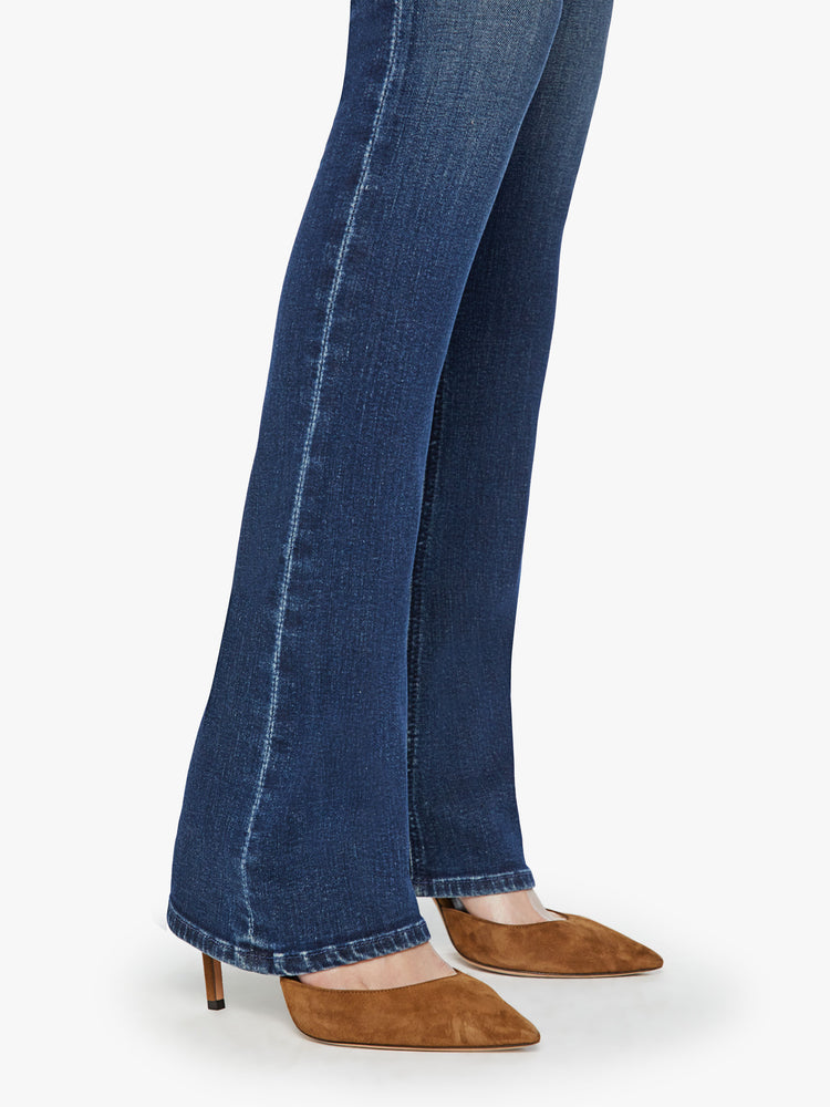 Hem view of a woman mid-rise flare with a long 34-inch inseam and a clean hem in a dark blue wash.