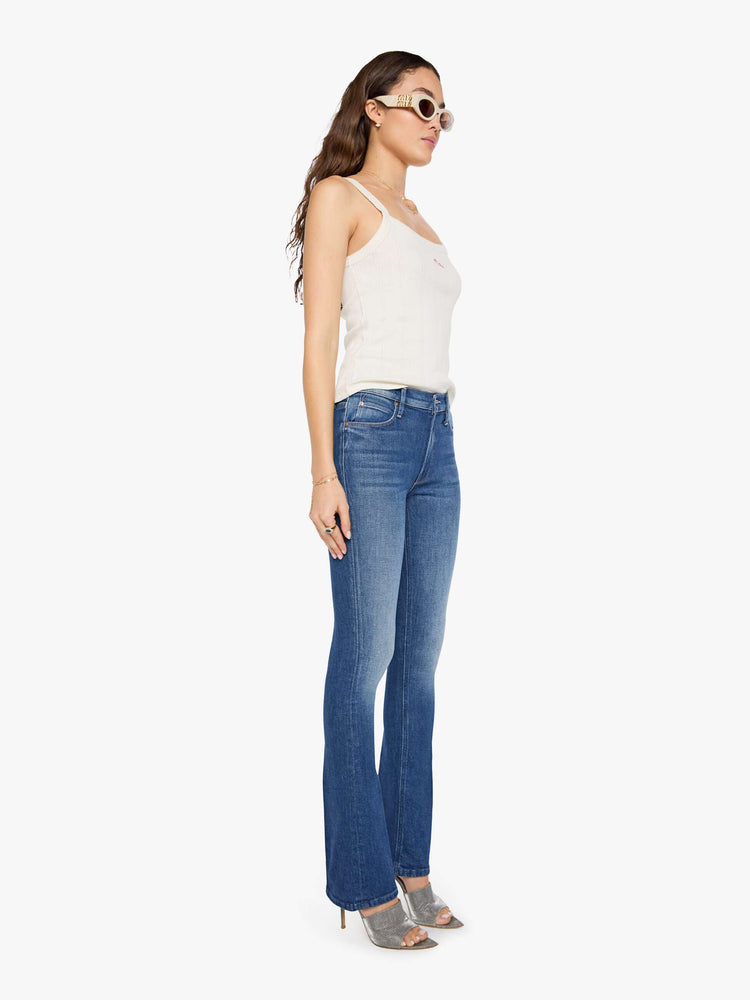 Side angle view of a woman in mid blue skinny flare with a mid rise, zip fly and a long 34-inch inseam with a clean hem.