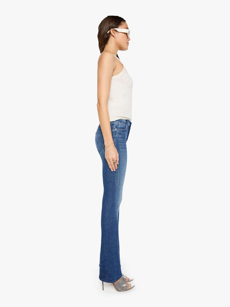 Side view of a woman in mid blue skinny flare with a mid rise, zip fly and a long 34-inch inseam with a clean hem.