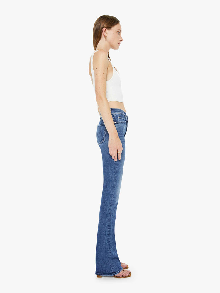 Side view of a woman in a skinny flare with a mid rise, zip fly and a long 34-inch inseam with a clean hem.