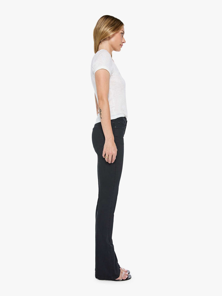 Side view of a womens black wash jean featuring a mid rise and skinny flare.