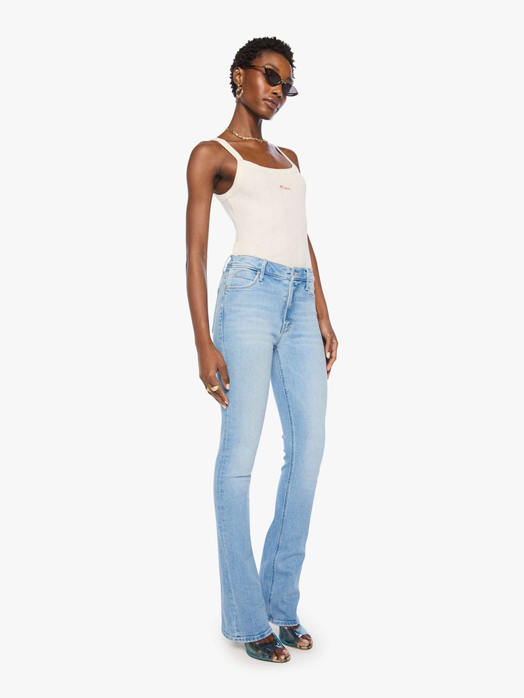 Side angle view of a woman in a light blue classic skinny flare with a mid rise, zip fly and a long 34-inch inseam with a clean hem.