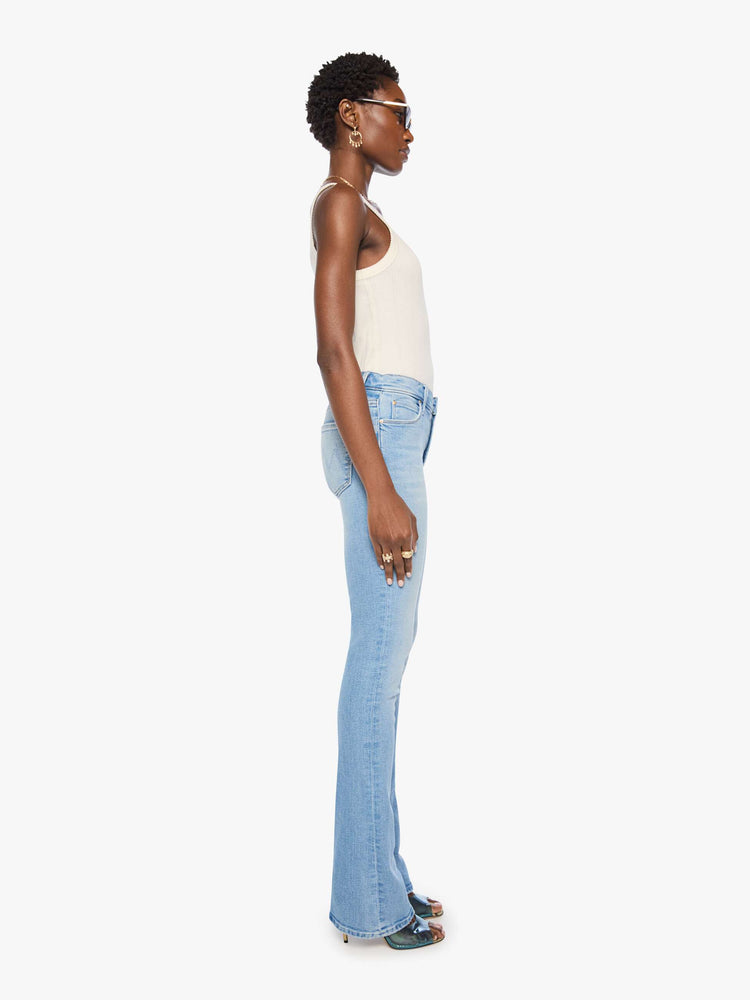 Side view of a woman in a light blue classic skinny flare with a mid rise, zip fly and a long 34-inch inseam with a clean hem.