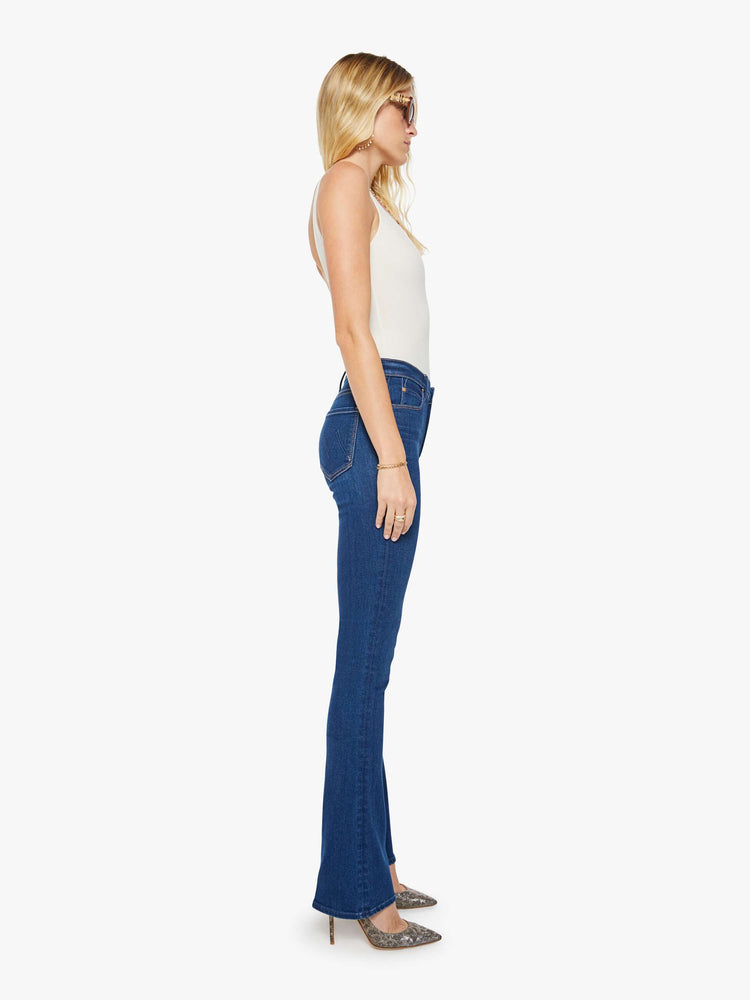 Side view of a woman in a skinny flare with a mid rise, zip fly and a long 34-inch inseam with a clean hem.