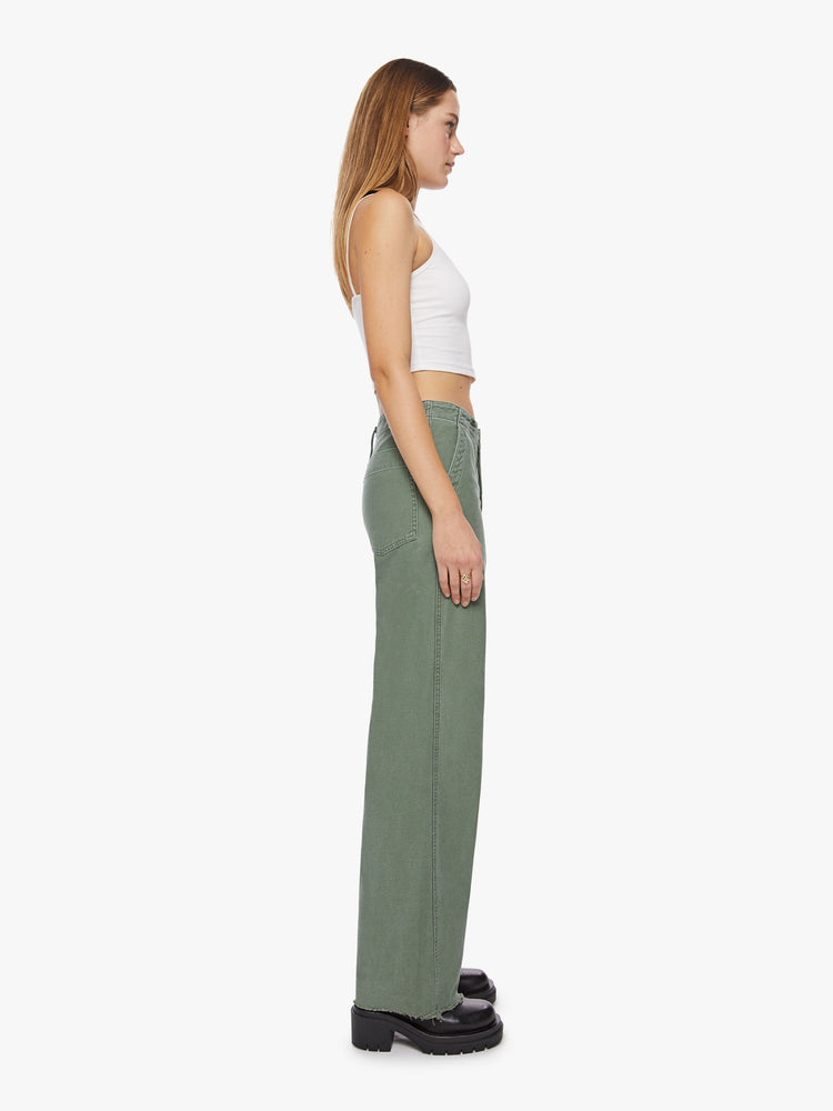 Side view a woman army green super high waisted pants with a loose straight leg, side slit pockets, a long 33.5-inch inseam and a frayed hem.