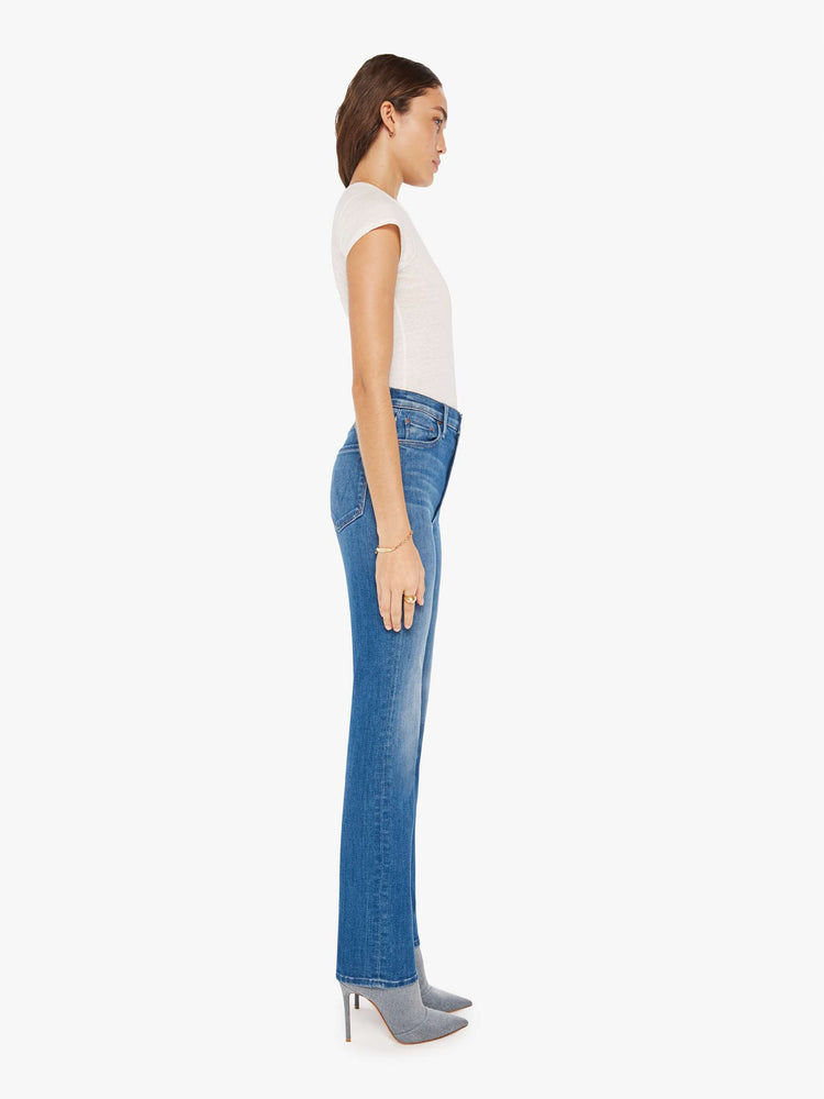 Side view of a woman mid blue high-waisted straight leg has a 31-inch inseam and a clean hem.