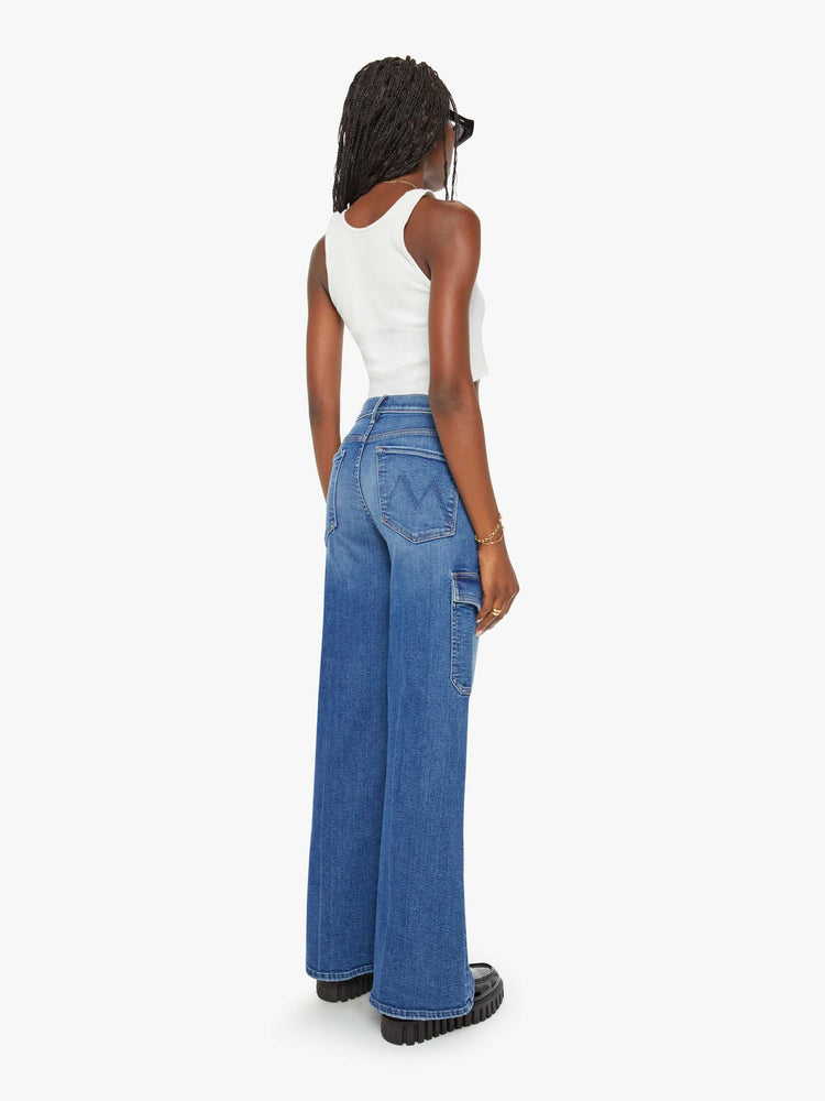 Back view of a woman med blue wide-leg cargo pants with a high rise, long 32-inch inseam and patch pockets on the thighs.