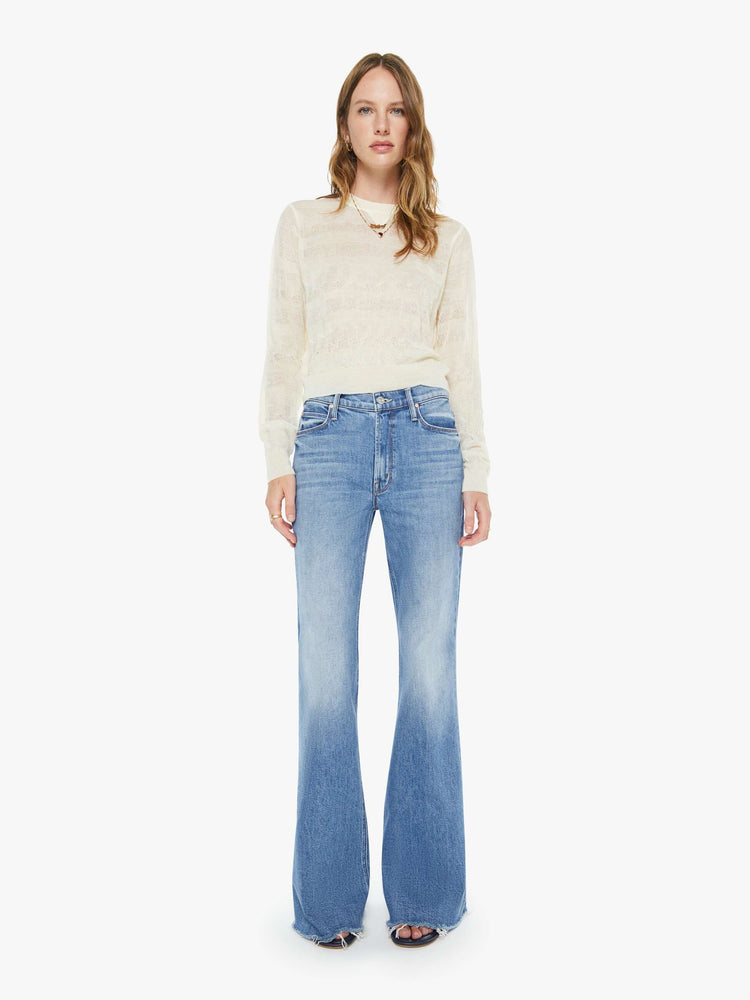 Front view of a woman in a vintage blue high-rise flare with a zip fly, long 34-inch inseam and a frayed hem.