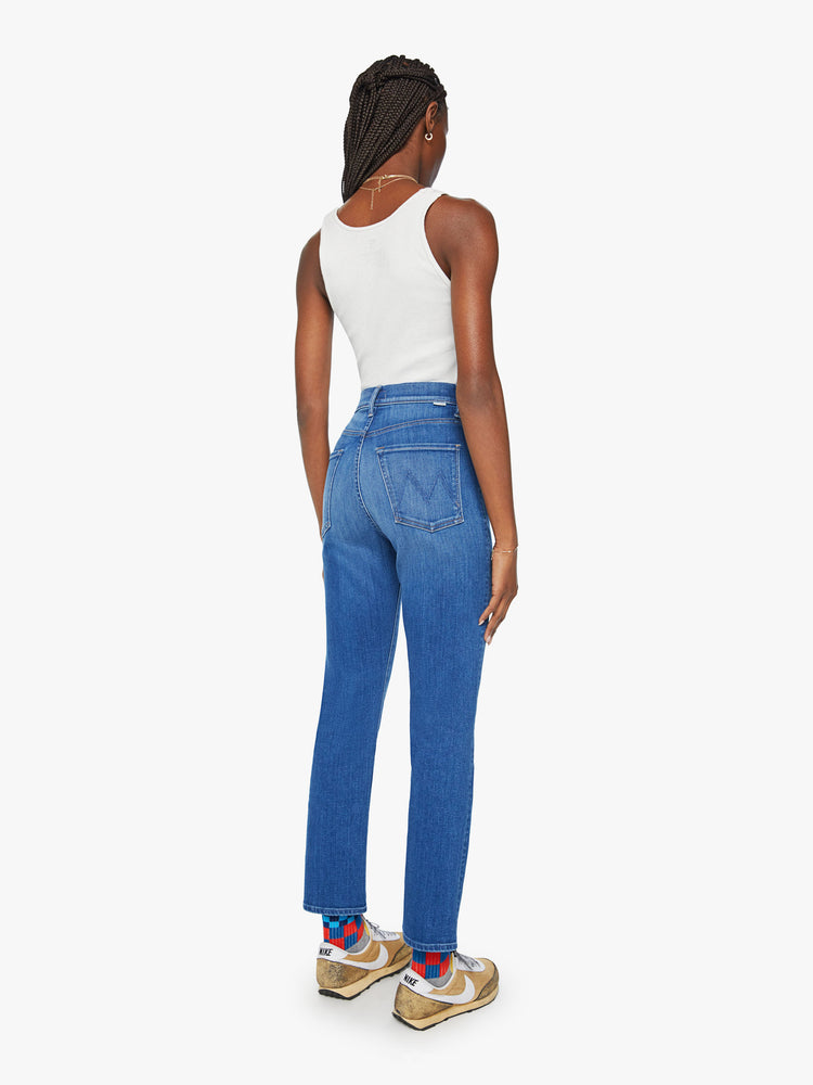 Back view of a woman slim straight leg with a button fly, low-set back pockets, high waist and a 29-inch inseam in mid blue wash.