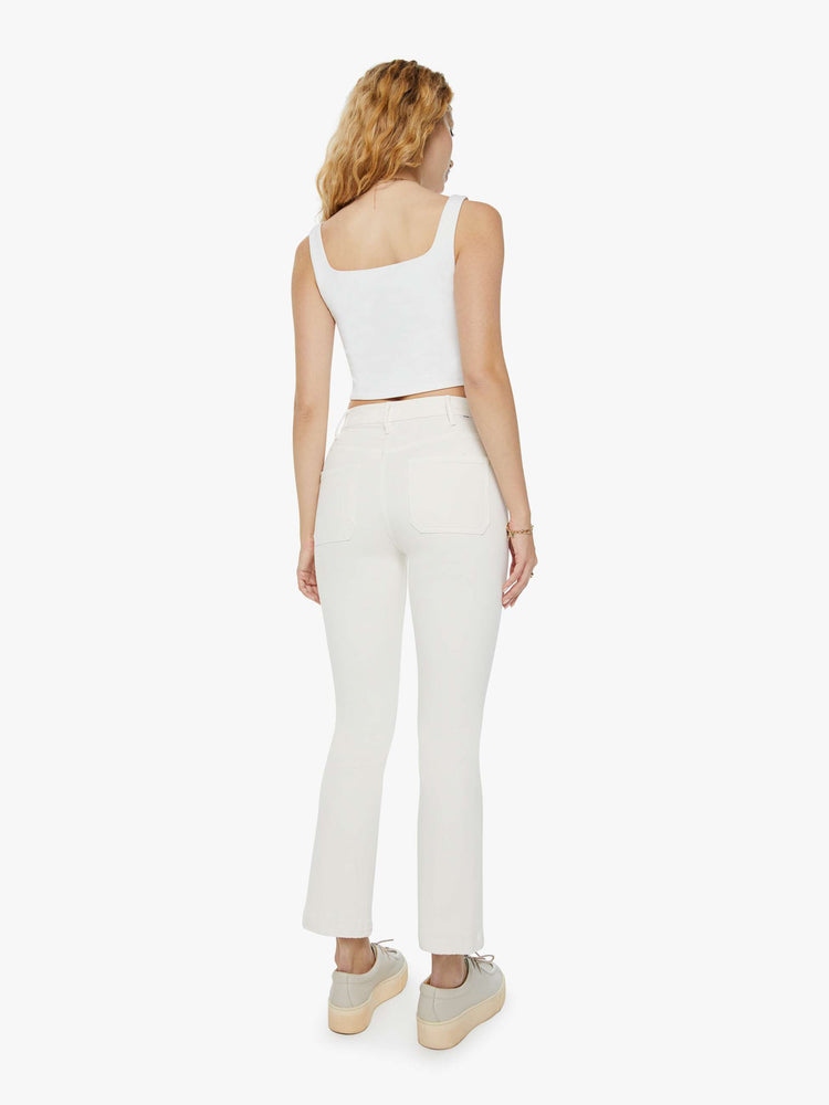 Back view of a woman in a high-rise ivory flare with patch pockets and a clean hem and tonal hardware. Paired with a white tank top and sneakers.