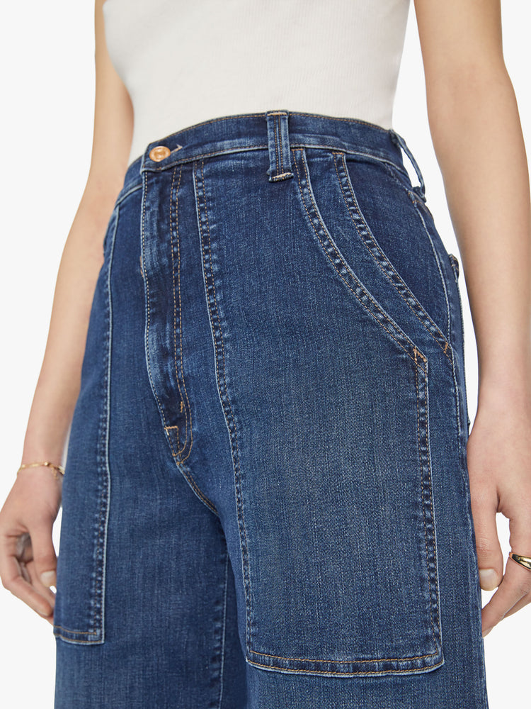 Close up view of a woman wide straight-leg jeans with a super high rise, oversized double patch pockets and a clean hem in a dark blue wash.