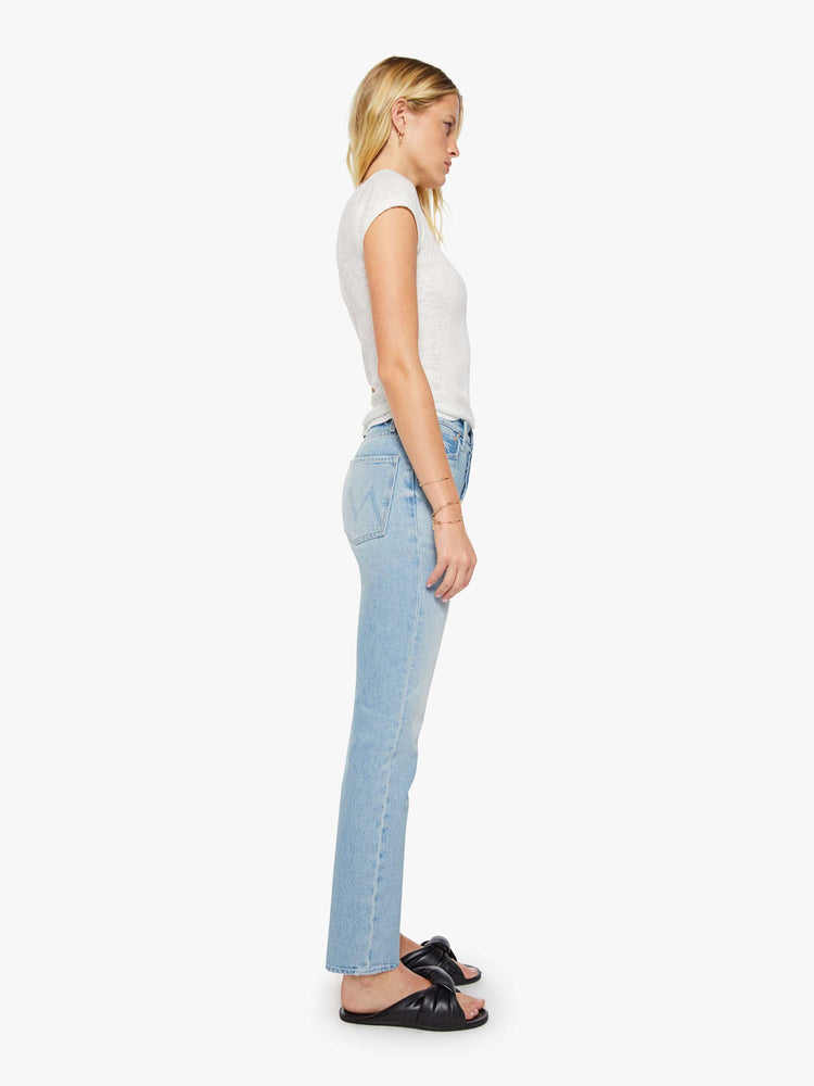 Side view of a woman in a light blue high-waisted straight-leg jeans with a button fly, 31-inch inseam and a clean hem.