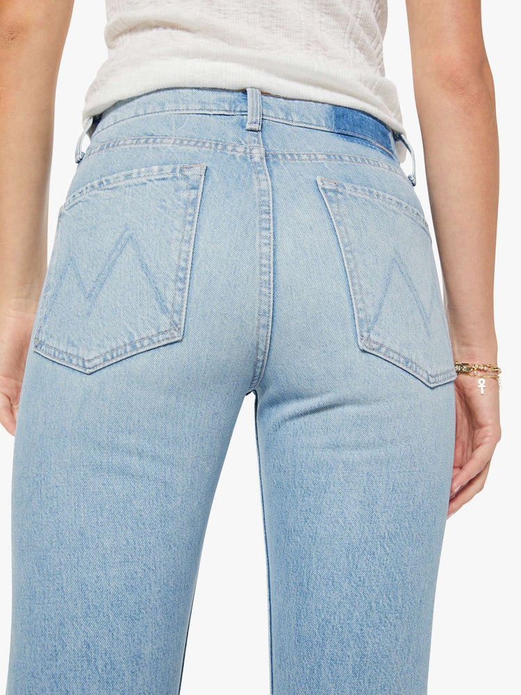 Close up view of a woman in a light blue high-waisted straight-leg jeans with a button fly, 31-inch inseam and a clean hem.