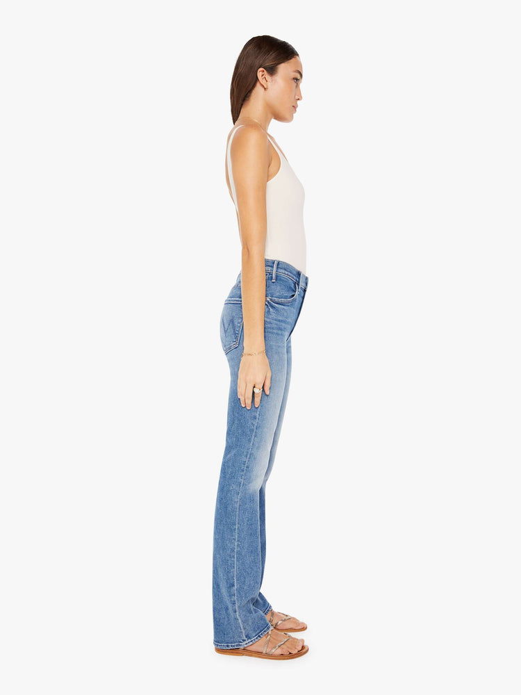 Side view of a womens medium blue wash jean featuring a high rise and a flare leg.