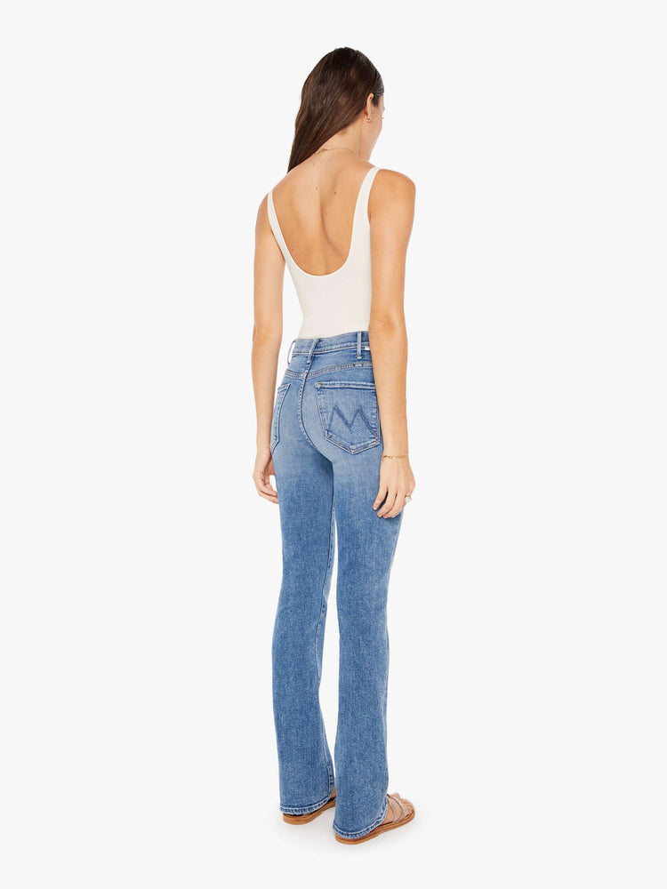 Back 3/4 view of a womens medium blue wash jean featuring a high rise and a flare leg.