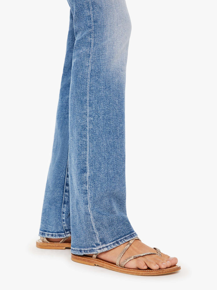 Close up view of a womens medium blue wash jean featuring a high rise and a flare leg.