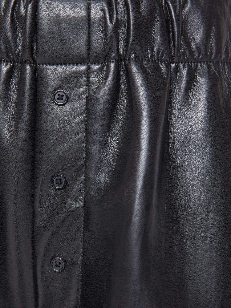 Swatch view of a woman in a black high-rise pants with an elastic waistband, loose wide leg, decorative exposed button-fly and a long 31-inch inseam. 