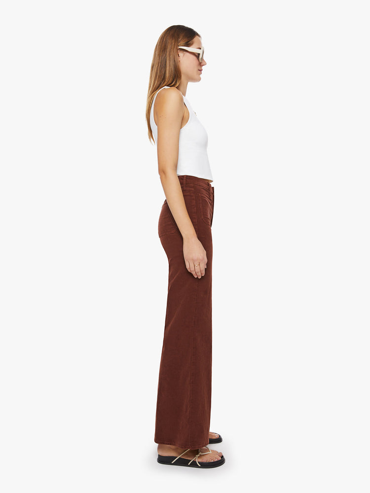 Side view of a woman wide-leg pants with a high rise, long inseam, patch pockets and a clean hem in a maroon-brown hue.