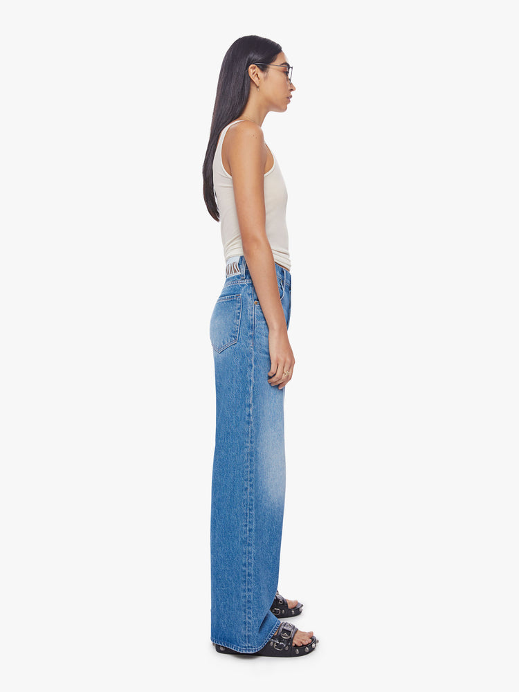 Side view of a woman mid-rise wide leg jean with a button fly, slouchy, loose fit and a 30-inch inseam in a mid-blue wash.
