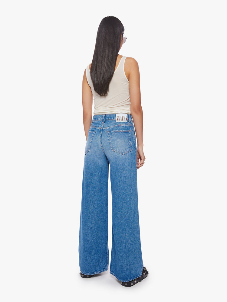 Back view of a woman mid-rise wide leg jean with a button fly, slouchy, loose fit and a 30-inch inseam in a mid-blue wash.