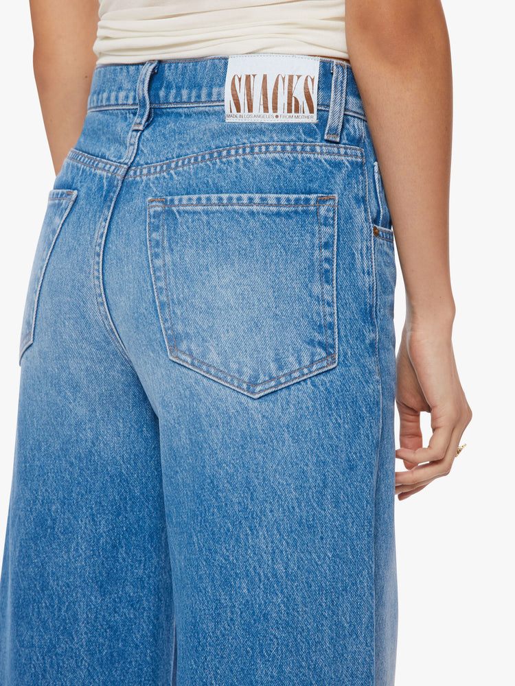 Waist back view of a woman mid-rise wide leg jean with a button fly, slouchy, loose fit and a 30-inch inseam in a mid-blue wash.