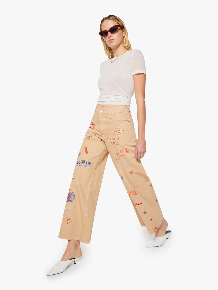 Walking view of a woman in a khaki with colorful embroidery  wide-leg jeans are designed with a loose fit, button fly and a 30-inch inseam with a clean hem.  
