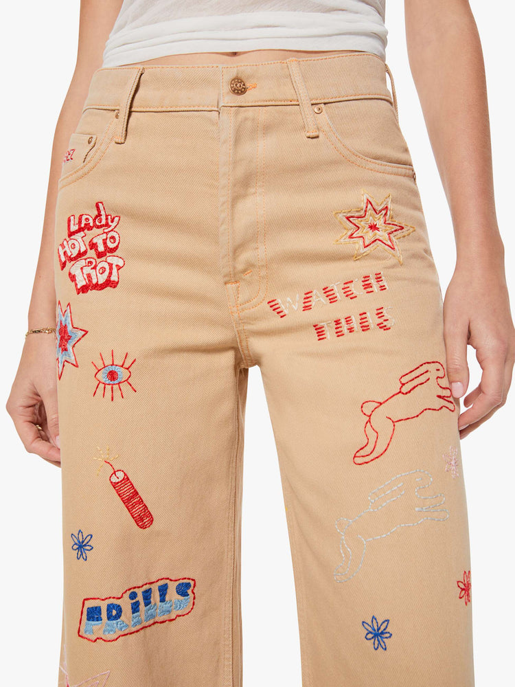 Close up view of a woman in a khaki with colorful embroidery  wide-leg jeans are designed with a loose fit, button fly and a 30-inch inseam with a clean hem.  